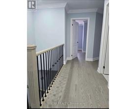 A hallway with a wooden floor and a black railing.