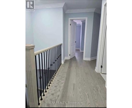 A hallway with a wooden floor and a black railing.