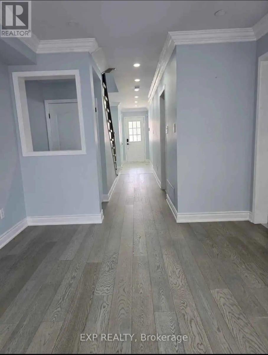 A hallway with wood flooring and white walls.