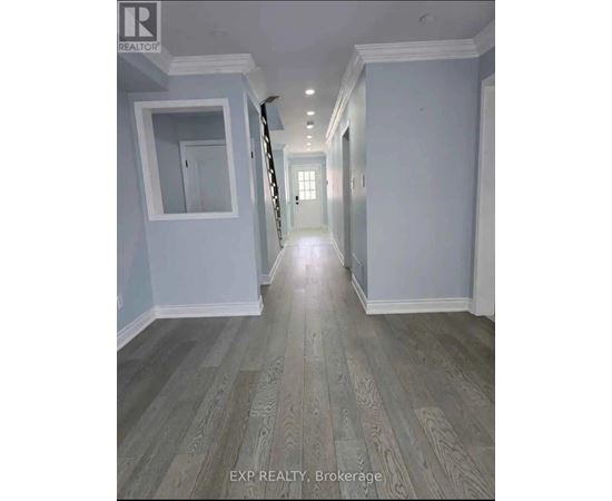 A hallway with wood flooring and white walls.
