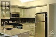 A kitchen with a refrigerator, microwave, and oven.