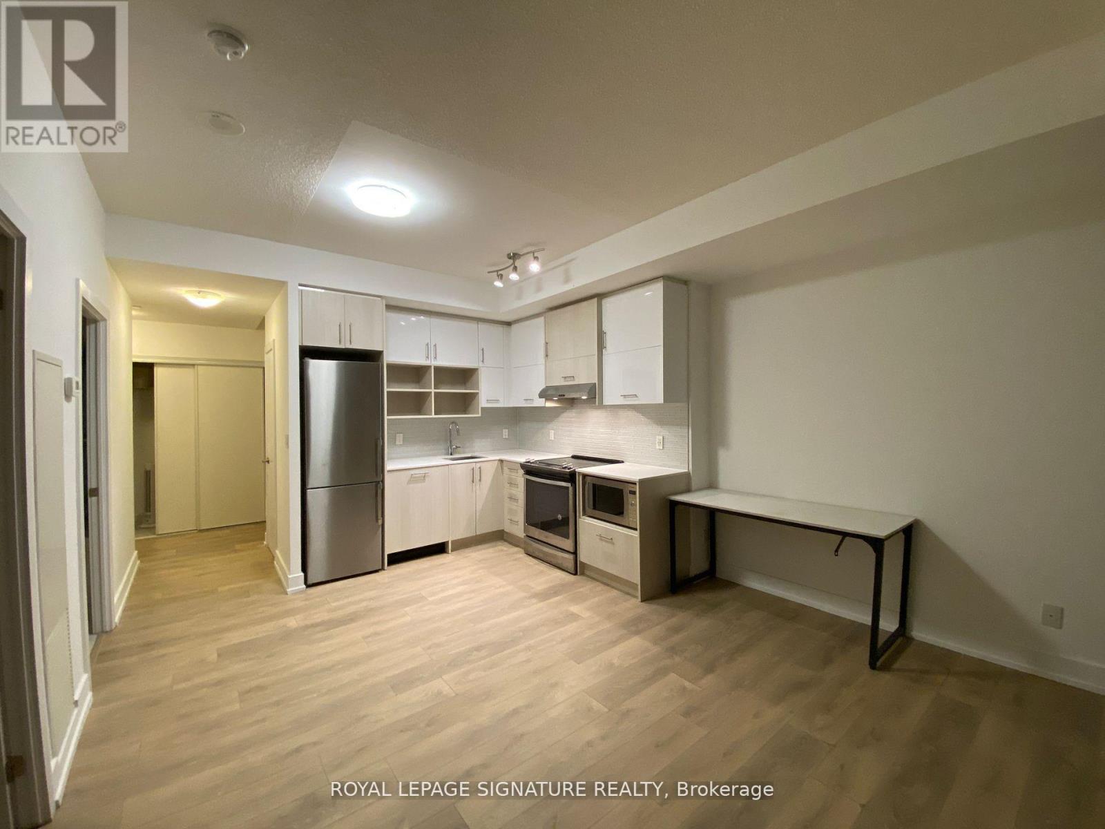A kitchen with white cabinets and a wooden floor.