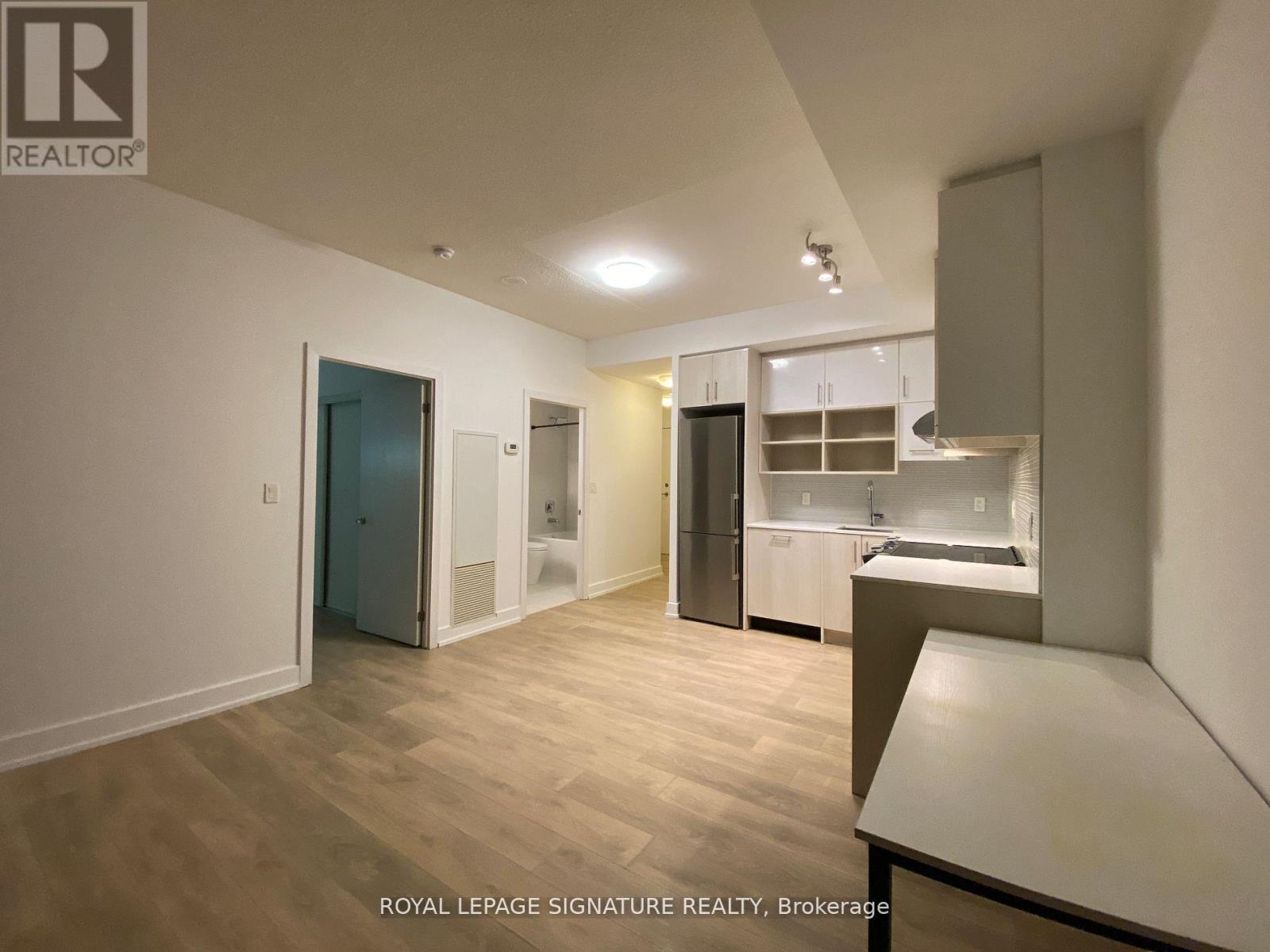 A well-lit, empty apartment with a kitchen area and a dining table.
