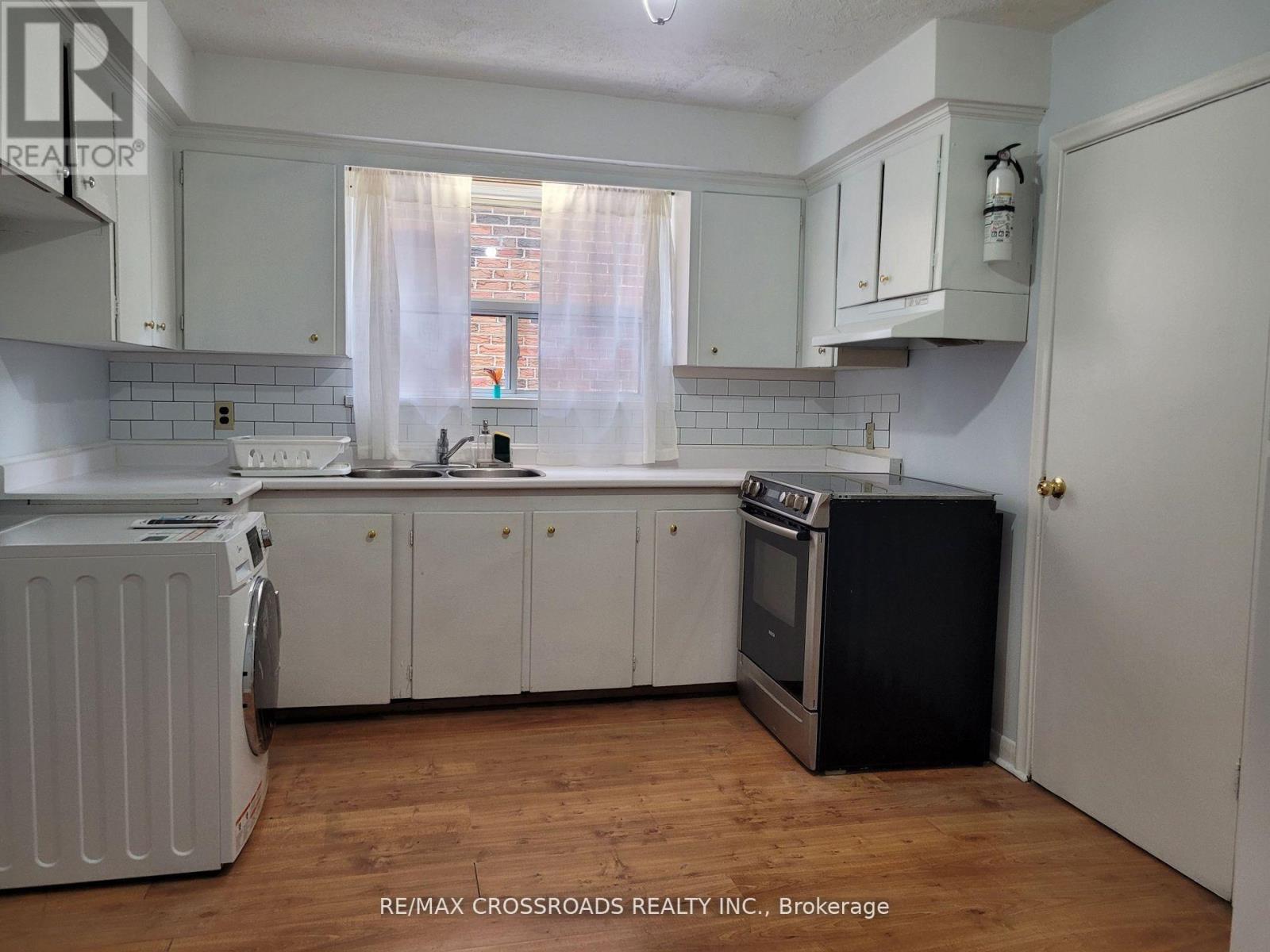 A kitchen with white cabinets and a black fridge.