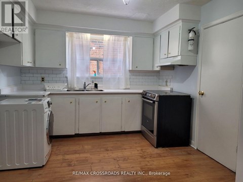 A kitchen with white cabinets and a black fridge.