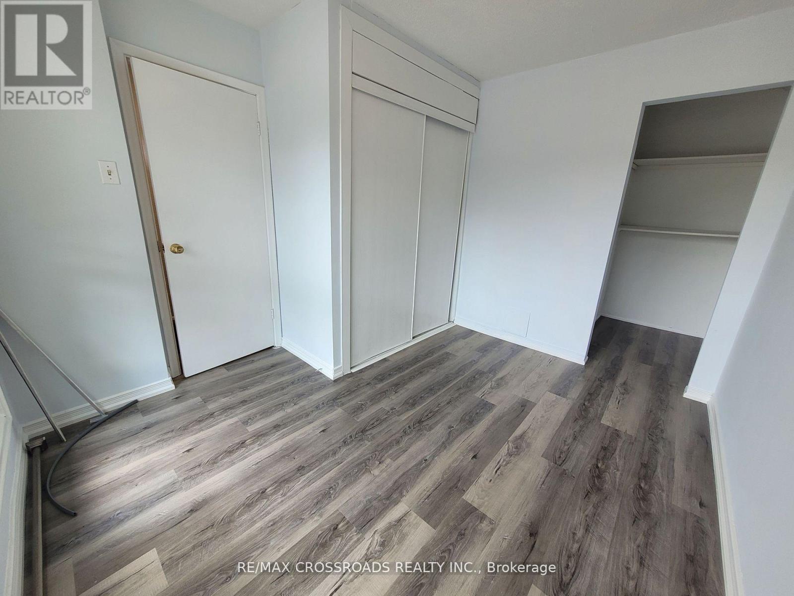 A room with wooden flooring and white walls, with a door on the left and a closet on the right.