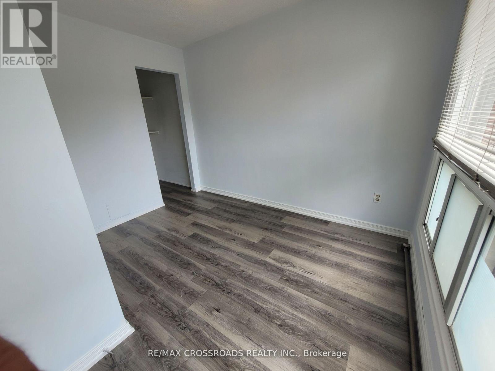 A room with wooden flooring and a window on the right side.
