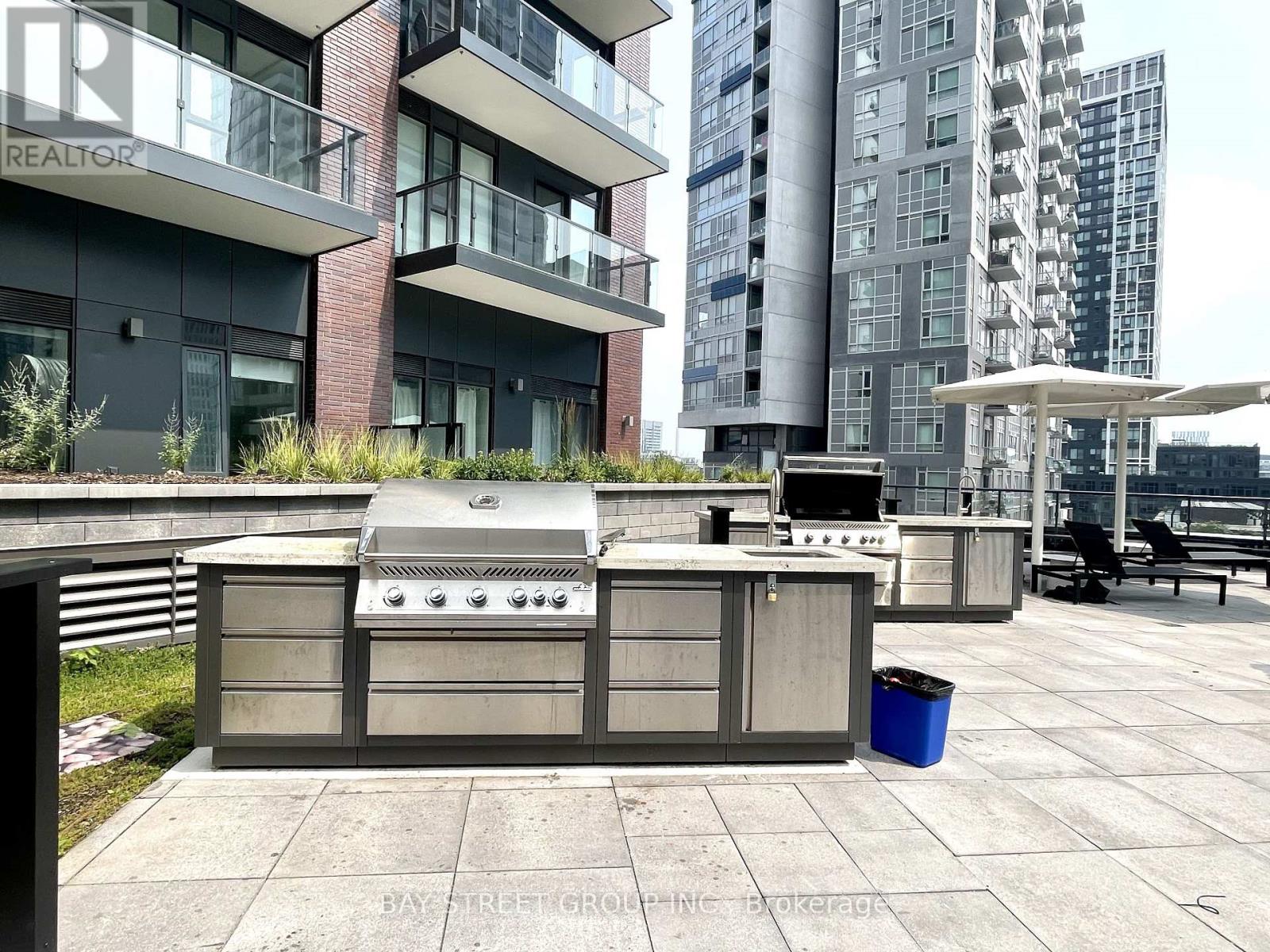 A BBQ grill is on a patio in front of apartment buildings.