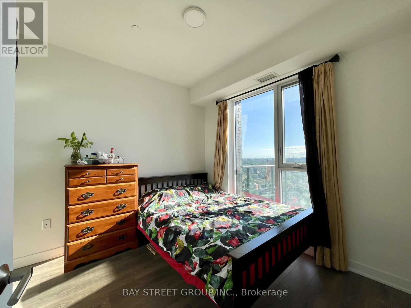 A bedroom with a bed, dresser, and window.