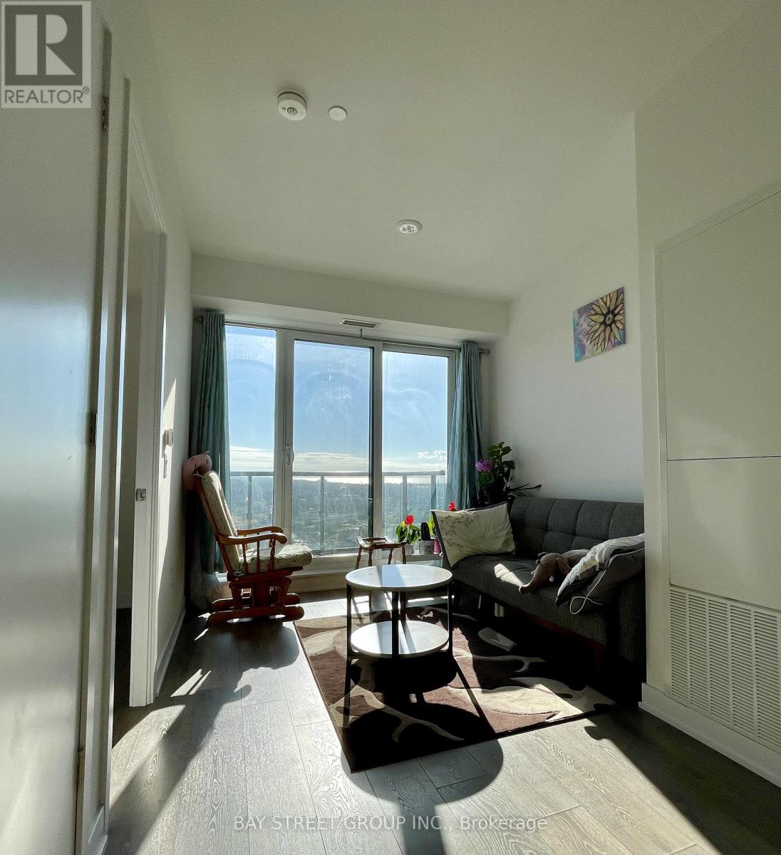 A living room with a couch, chair, and table with a view of the city.
