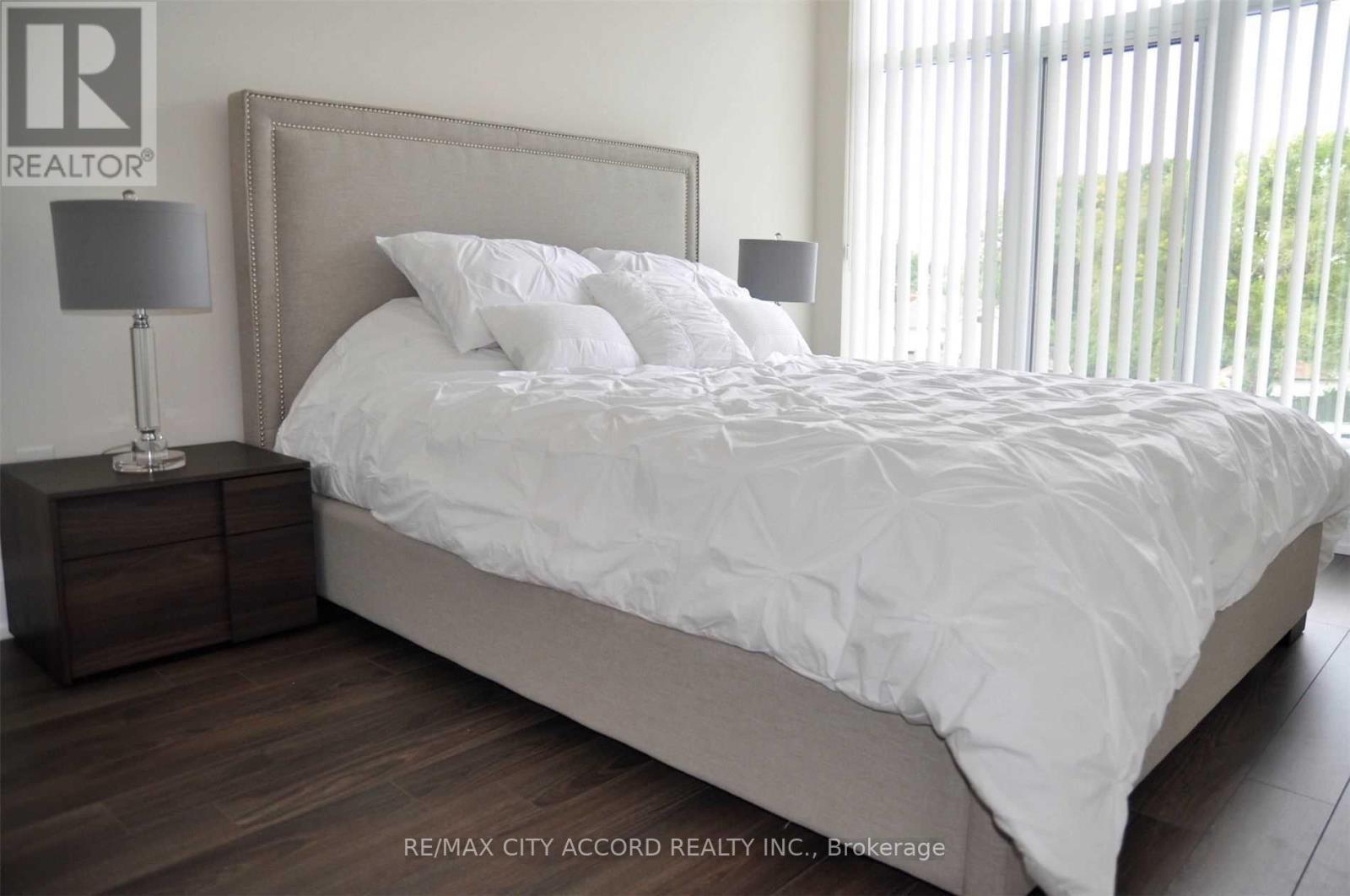 A bedroom with a large bed and a nightstand with a lamp.