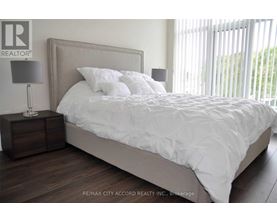 A bedroom with a large bed and a nightstand with a lamp.