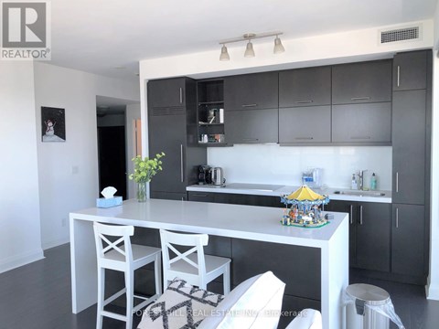 A kitchen with white cabinets and a white island with a yellow umbrella on it.