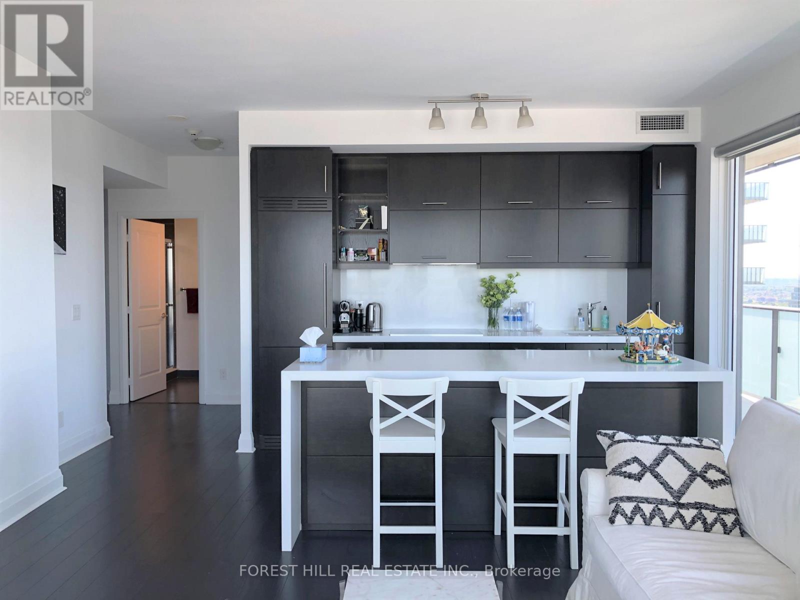 A modern kitchen with a white island and bar stools.