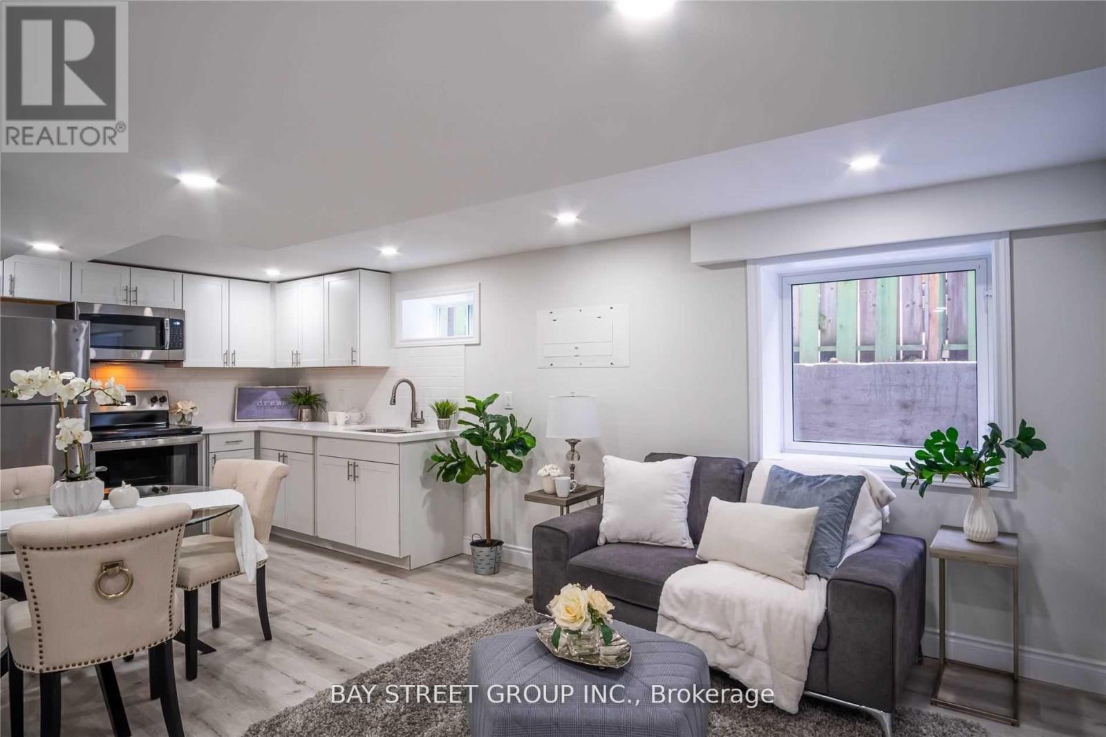 A well-lit living room with a grey couch and a dining table set up.