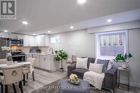 A well-lit living room with a grey couch and a dining table set up.
