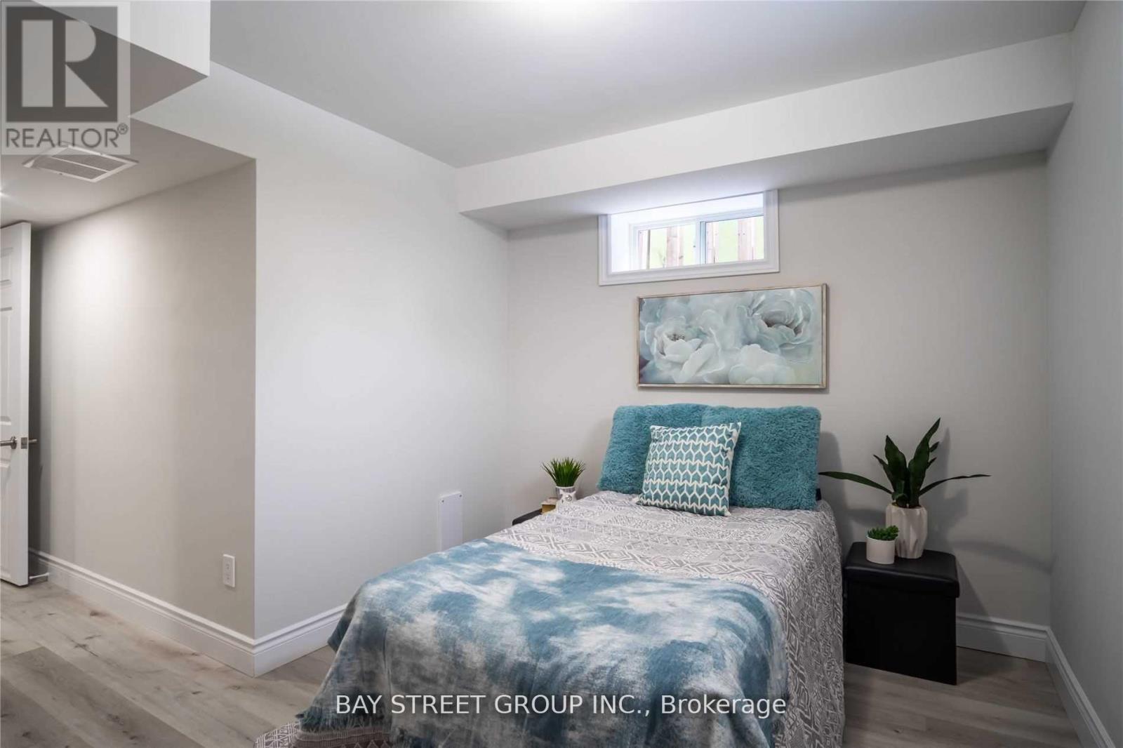 A bedroom with a bed, pillows, and a small table with a plant on it.