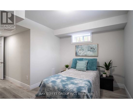 A bedroom with a bed, pillows, and a small table with a plant on it.