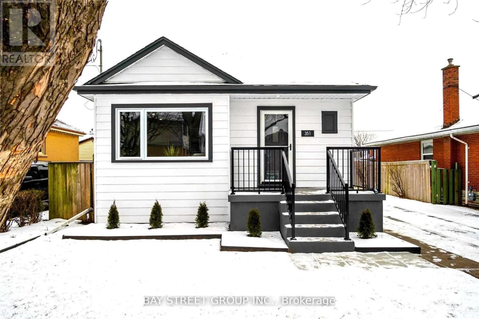 A small white house with a black roof and a black railing on the porch.