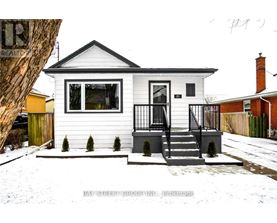 A small white house with a black roof and a black railing on the porch.