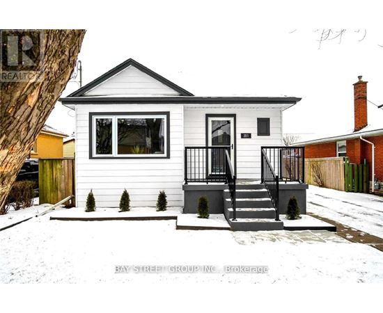 A small white house with a black roof and a black railing on the porch.