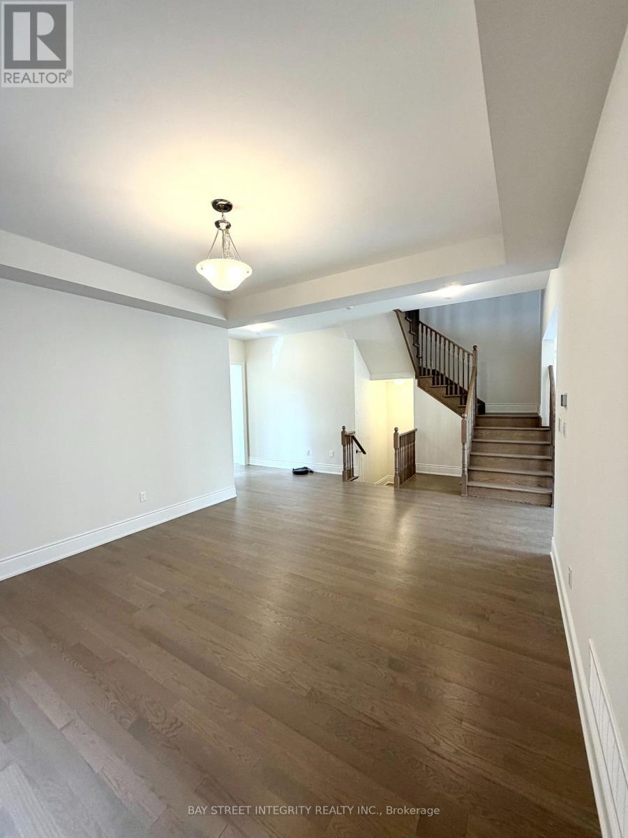 A spacious room with wooden floors and a staircase.