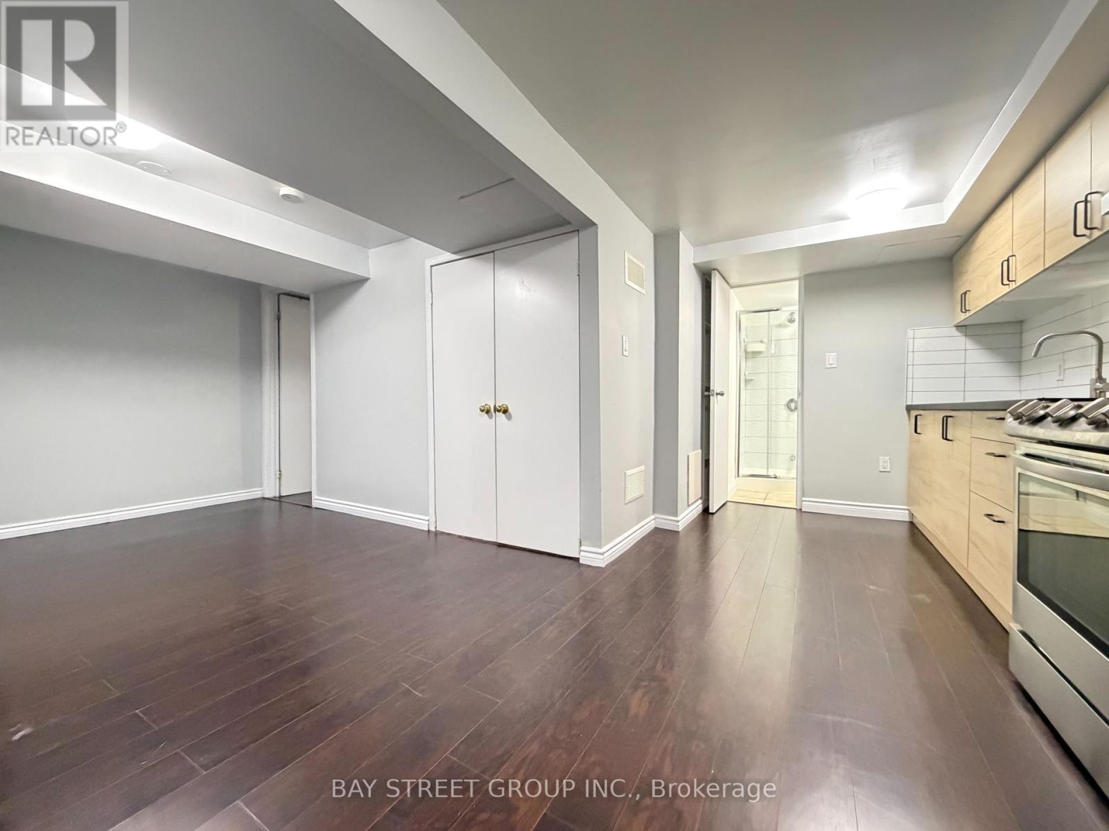 A spacious kitchen with white cabinets and a wooden floor.