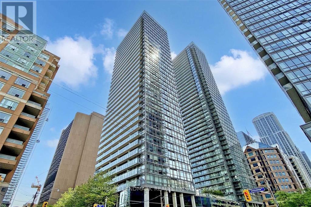 A tall glass building stands in the middle of a cityscape.