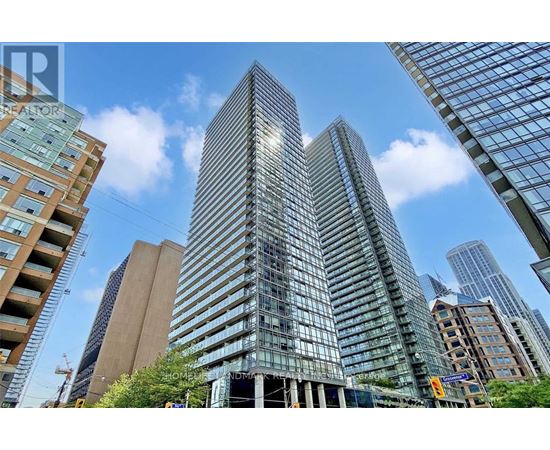 A tall glass building stands in the middle of a cityscape.