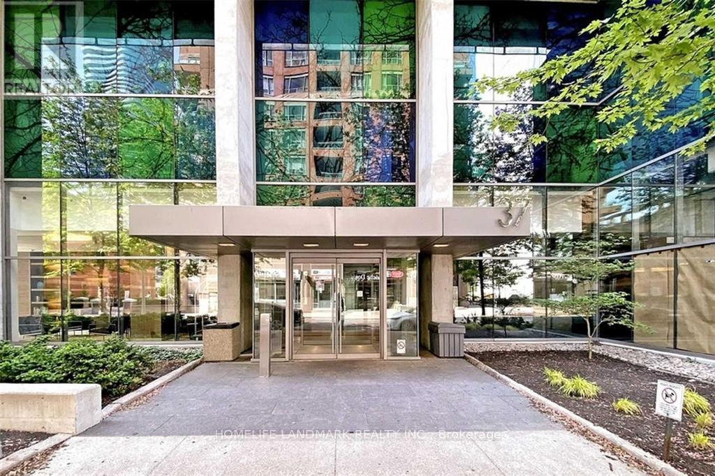 The image shows a modern building entrance with glass walls and a concrete structure.