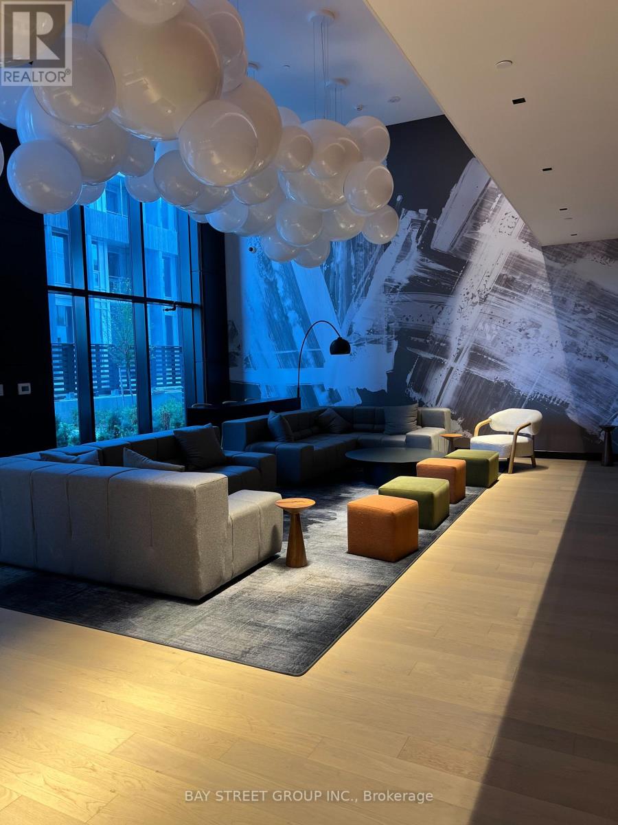 A room with a long couch and a wall with a black and white photo on it.