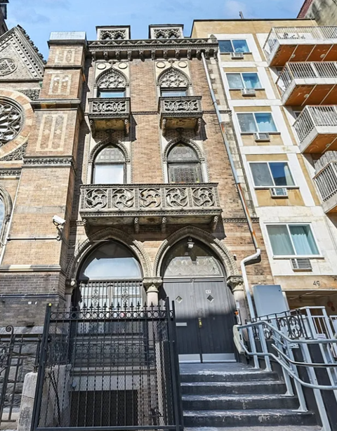 A tall building with a balcony and a gate in front of it.