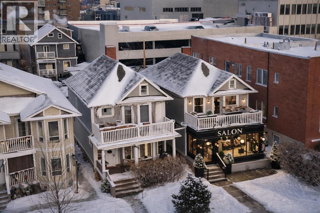 A house with a snow covered roof and a salon in the front.