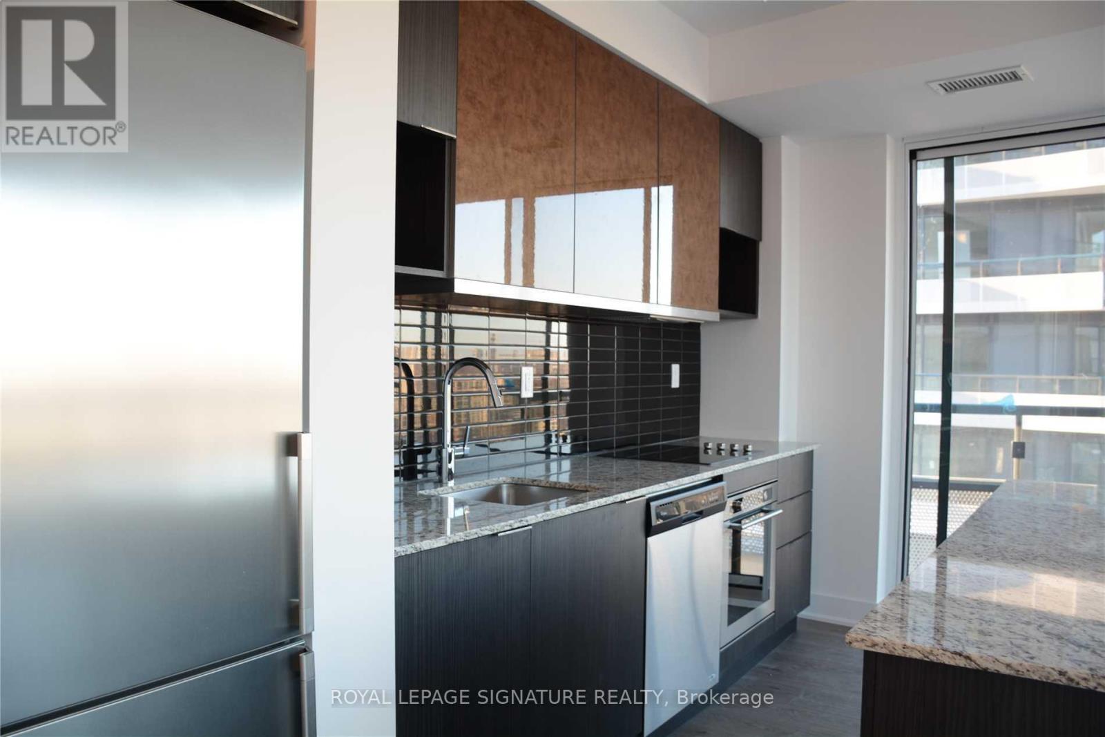 A modern kitchen with a stainless steel refrigerator and a marble countertop.