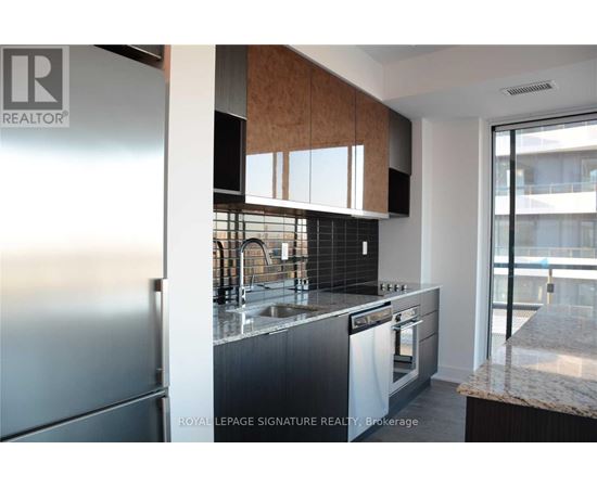 A modern kitchen with a stainless steel refrigerator and a marble countertop.