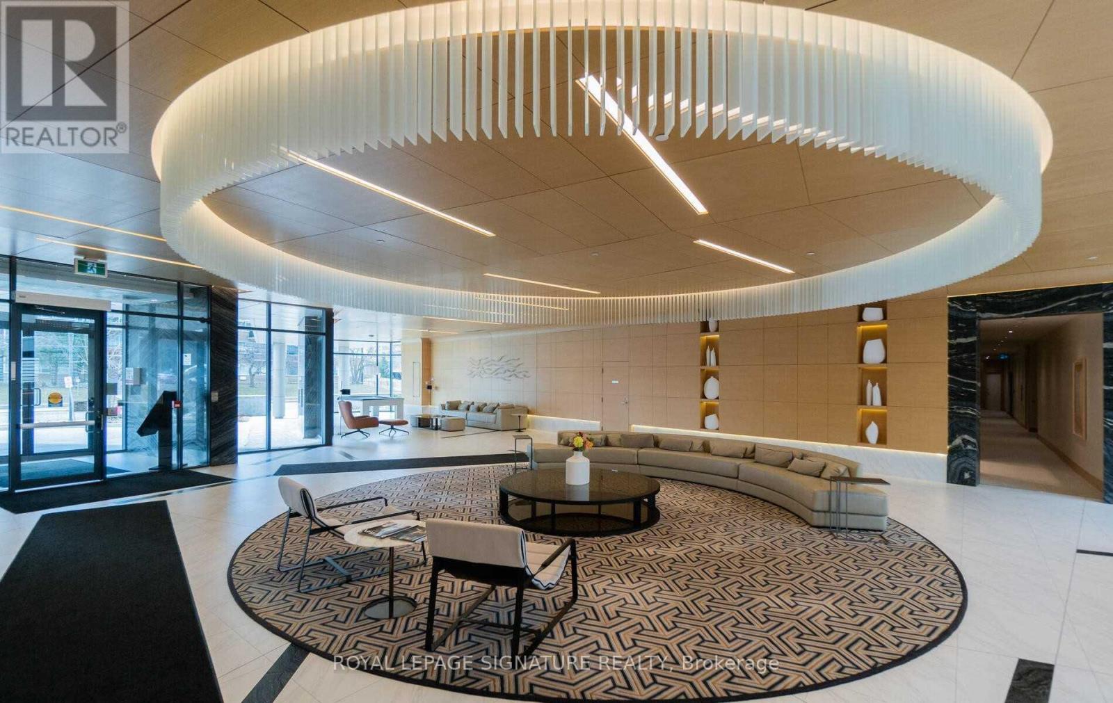 A modern living room with a circular light fixture and a patterned rug.