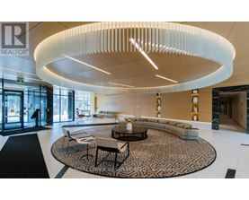 A modern living room with a circular light fixture and a patterned rug.