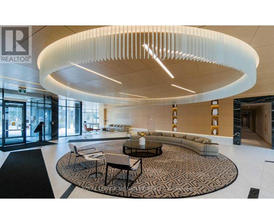A modern living room with a circular light fixture and a patterned rug.