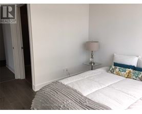A bedroom with a white bed and a lamp on a side table.