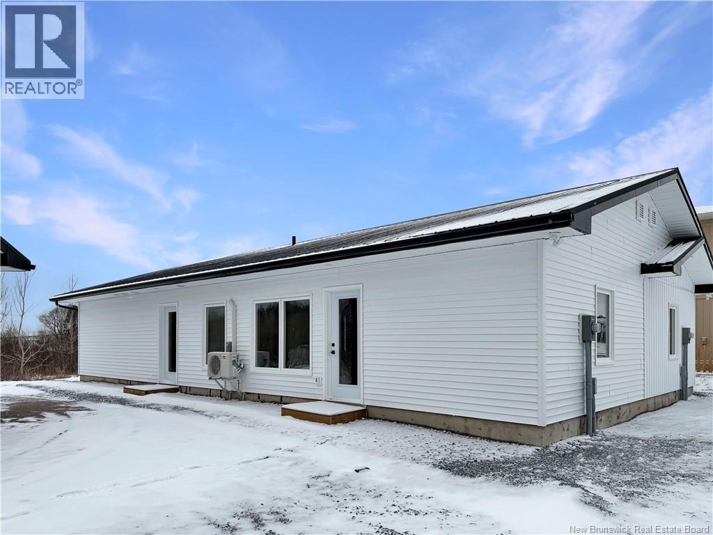 A white mobile home with a black roof and a snowy ground.