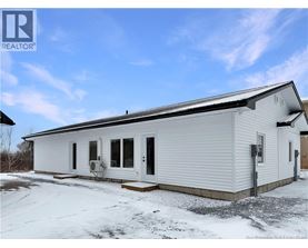 A white mobile home with a black roof and a snowy ground.