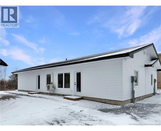 A white mobile home with a black roof and a snowy ground.