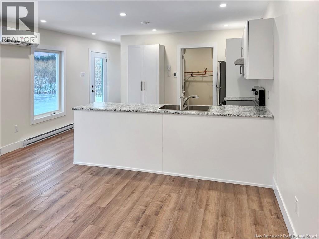 A kitchen with a white countertop and wooden flooring.