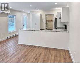 A kitchen with a white countertop and wooden flooring.