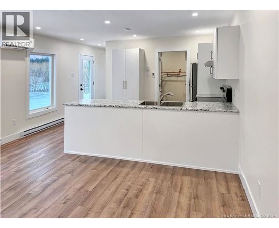 A kitchen with a white countertop and wooden flooring.