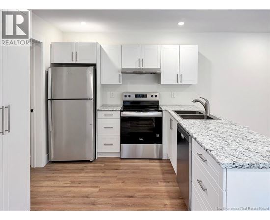A kitchen with a refrigerator, oven, and cabinets.