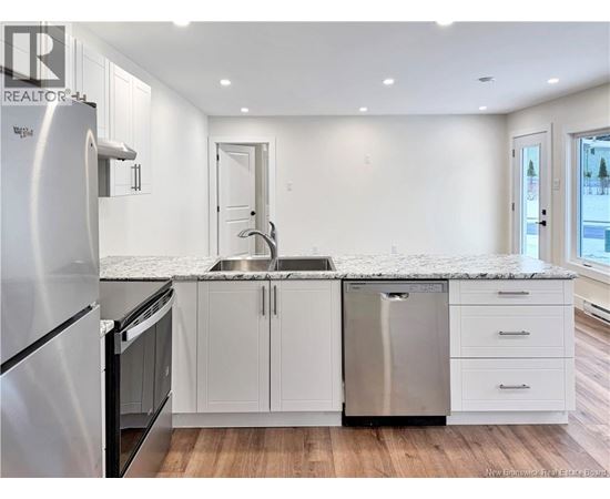 A modern kitchen with white cabinets and stainless steel appliances.