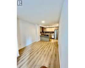 A kitchen area with wooden flooring and a stainless steel refrigerator.