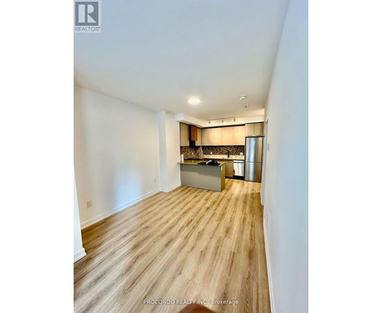 A kitchen area with wooden flooring and a stainless steel refrigerator.