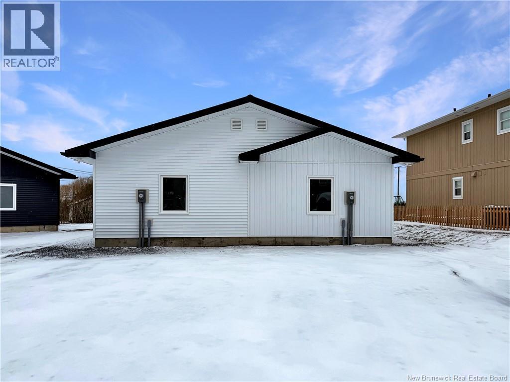 A white house with a black roof is in the snow.